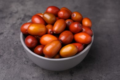 Photo of Ripe red dates in bowl on grey table, closeup