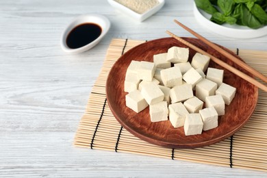 Delicious tofu with chopsticks on white wooden table