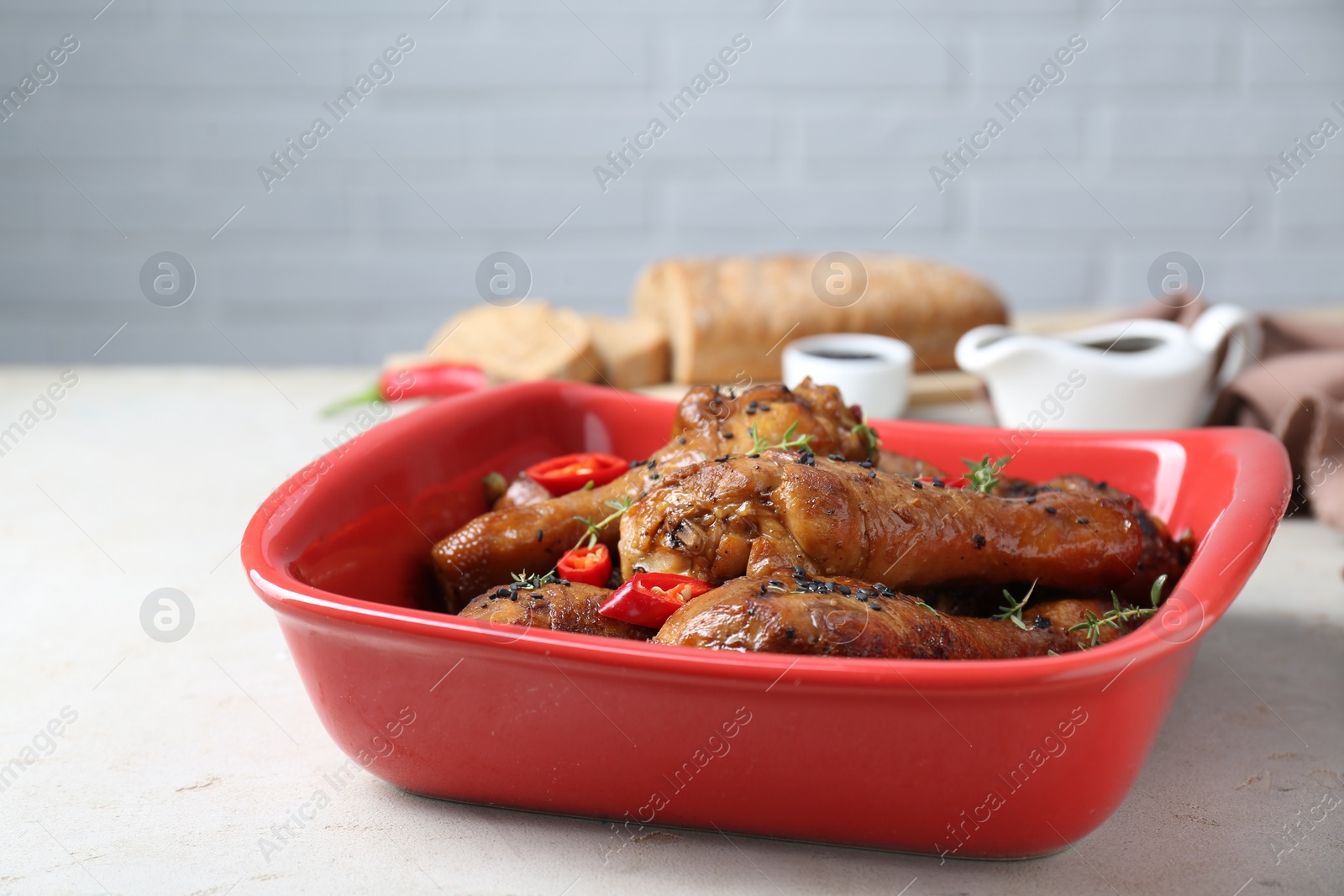 Photo of Chicken legs glazed with soy sauce, black sesame, chili pepper and thyme on light table, closeup. Space for text