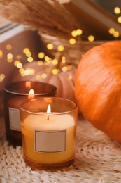 Photo of Scented candles and pumpkins on wicker mat indoors