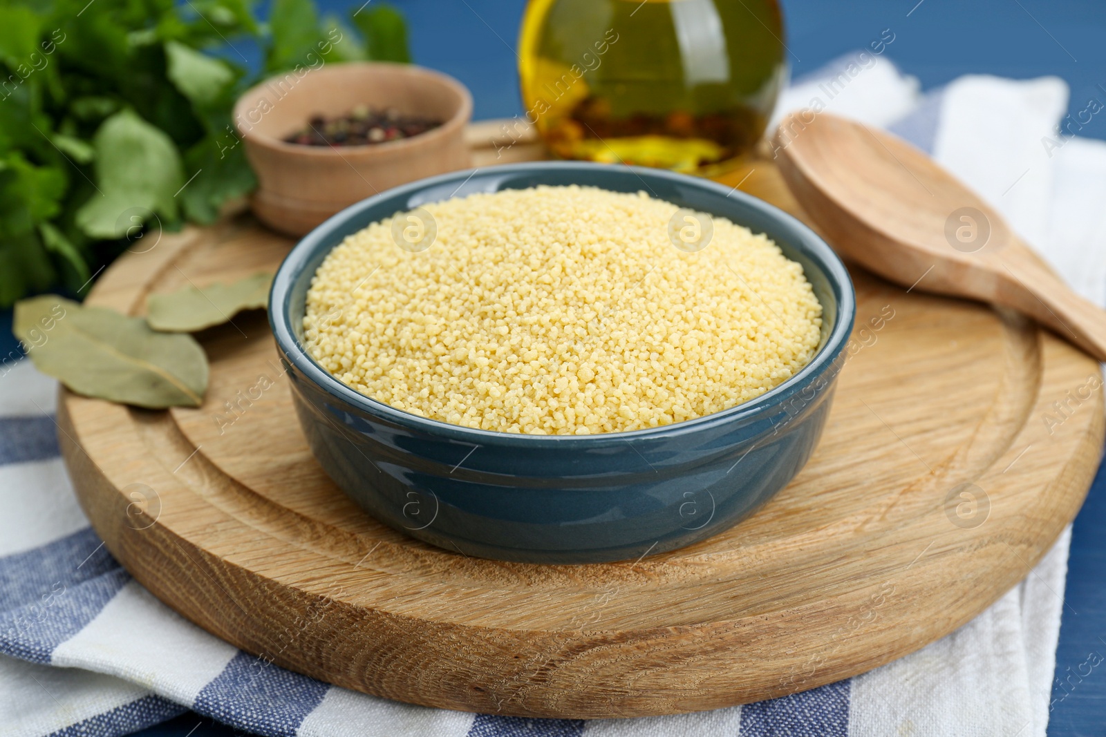 Photo of Bowl of raw couscous and ingredients on blue table
