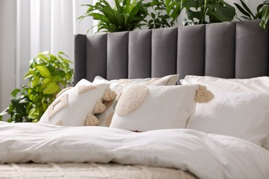 Photo of Comfortable bed with pillows, duvet and beautiful houseplants indoors. Stylish interior