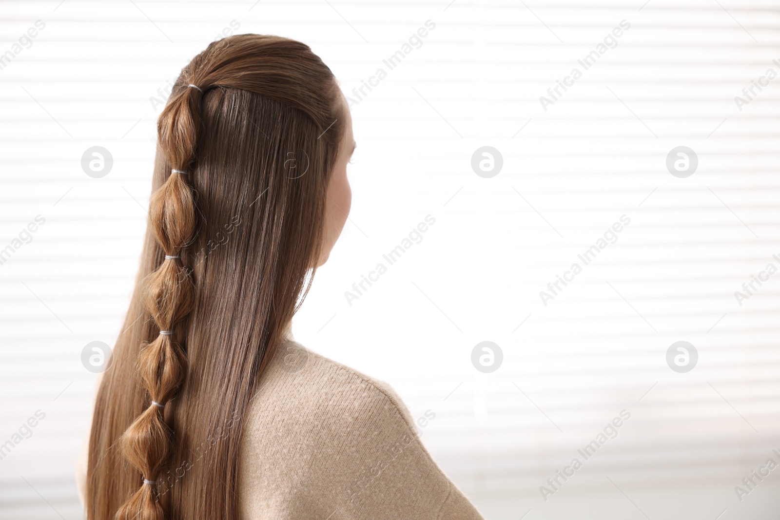 Photo of Woman with long braided hair indoors, back view. Space for text