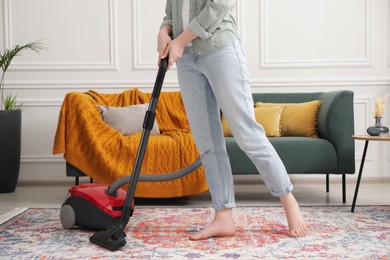 Photo of Woman cleaning carpet with vacuum cleaner at home, closeup