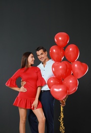 Photo of Beautiful couple with heart shaped balloons on dark background