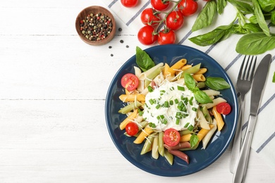 Delicious pasta with sour cream served on white wooden background, flat lay. Space for text