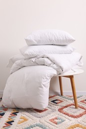 Photo of Soft pillows and duvet on side table near light wall indoors