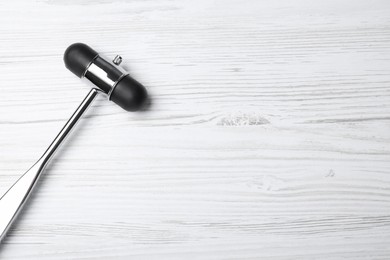 Photo of Reflex hammer on white wooden background, top view with space for text. Nervous system diagnostic