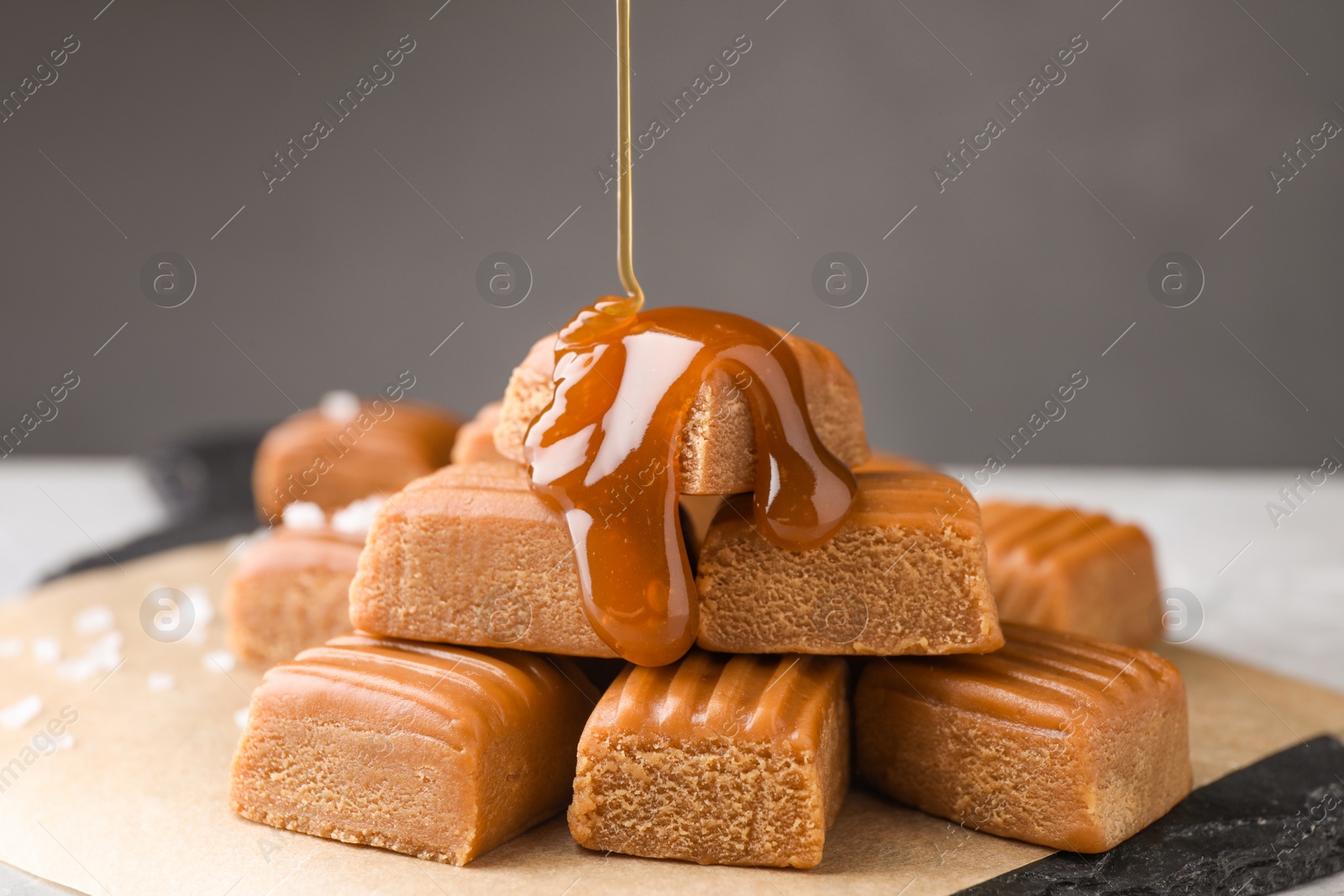 Photo of Pouring salted caramel on candies, closeup view