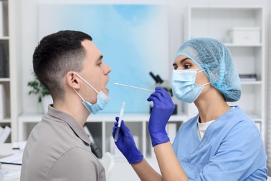 Laboratory testing. Doctor taking sample from patient's mouth with cotton swab in hospital