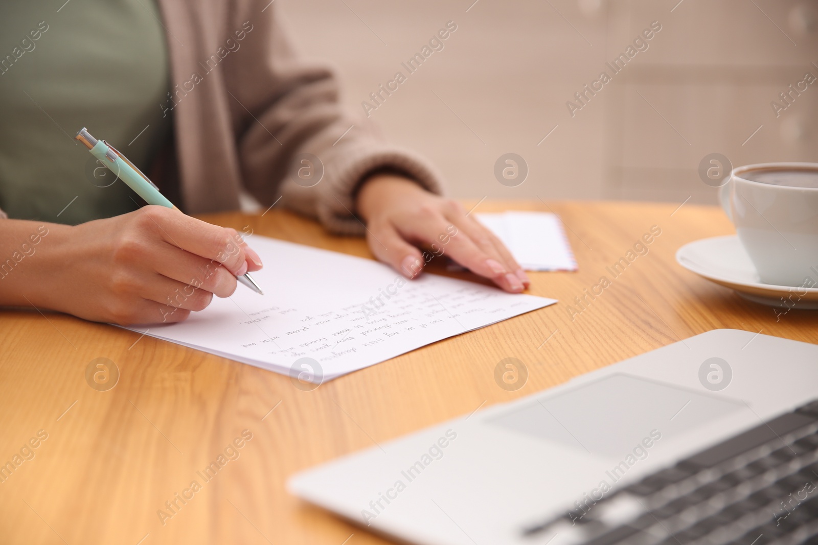 Photo of Woman writing letter at wooden table, closeup