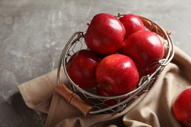 Photo of Basket with fresh ripe red apples on grey background
