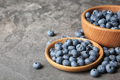 Photo of Dishware with juicy blueberries and space for text on color table