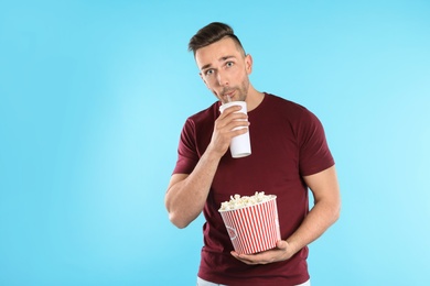 Man with popcorn and beverage during cinema show on color background
