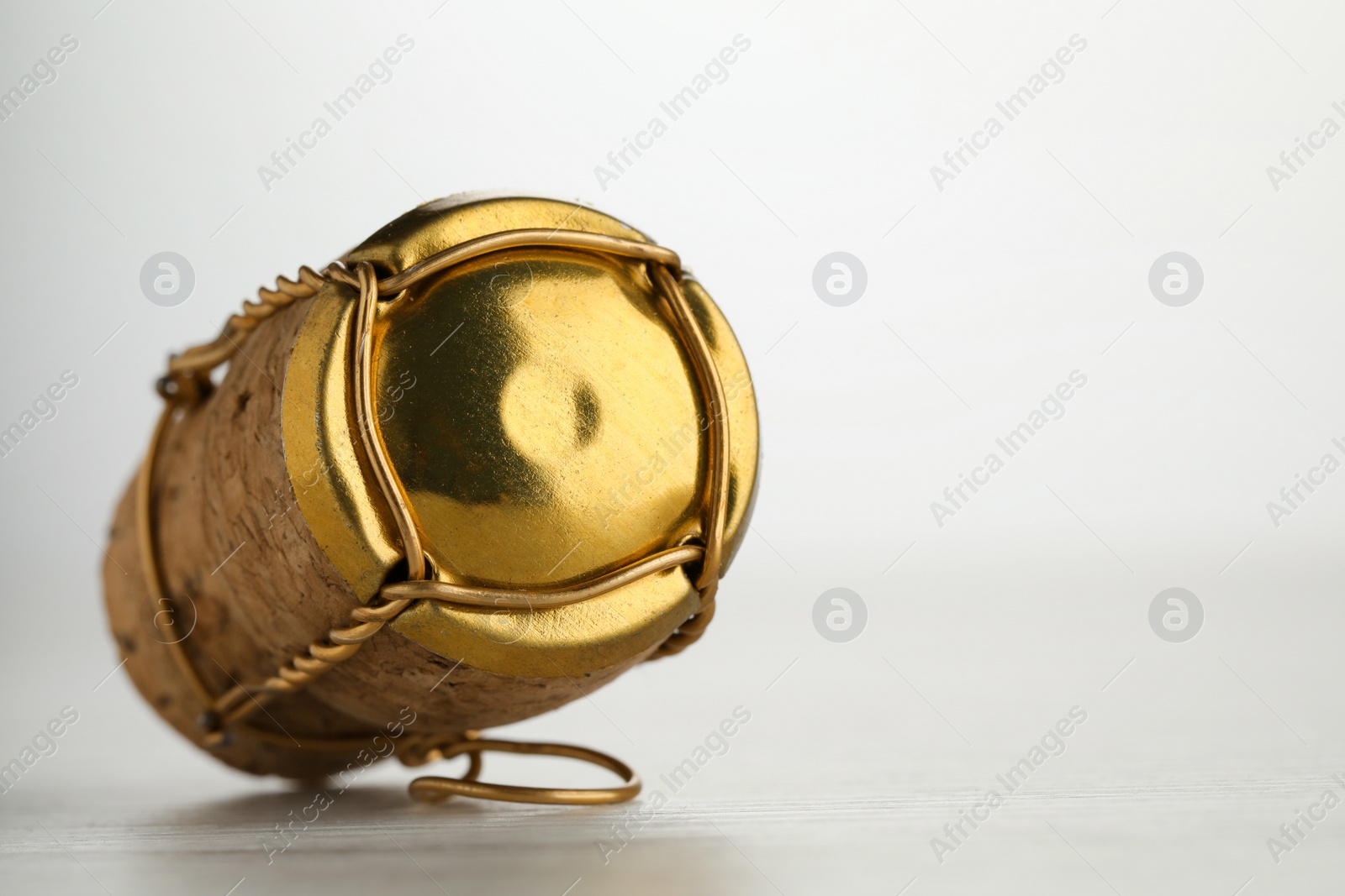 Photo of Cork of sparkling wine and muselet cap on white wooden table, closeup. Space for text
