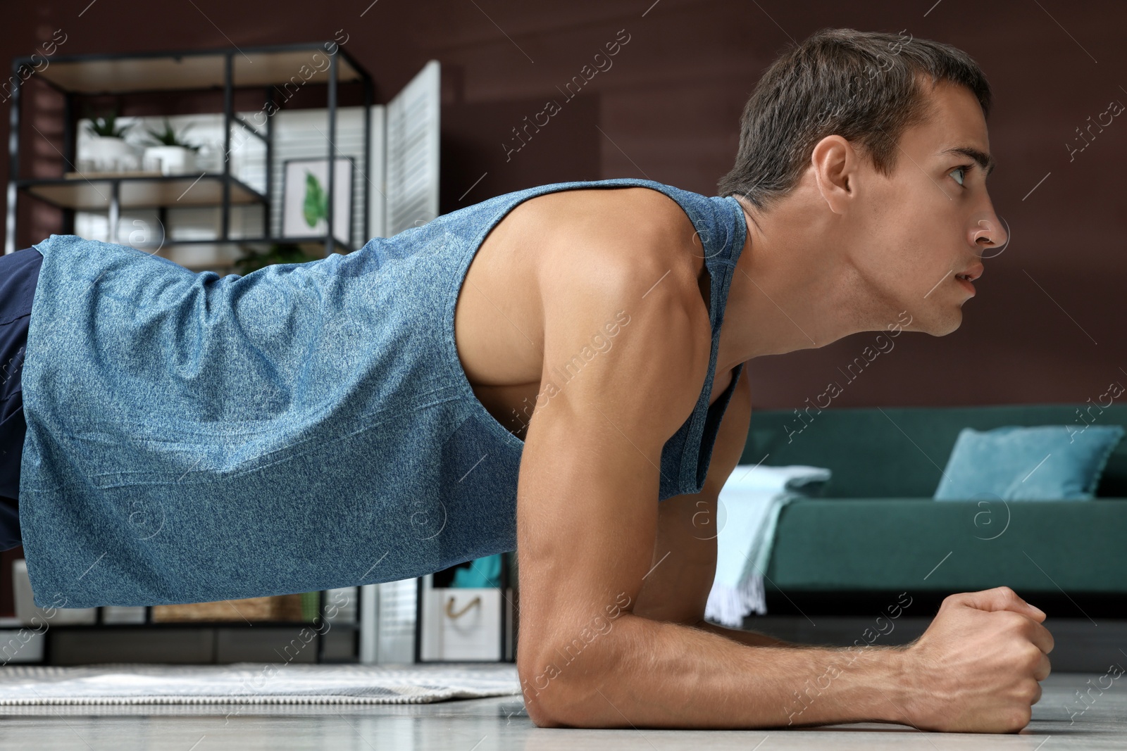 Photo of Handsome man doing plank exercise on floor at home