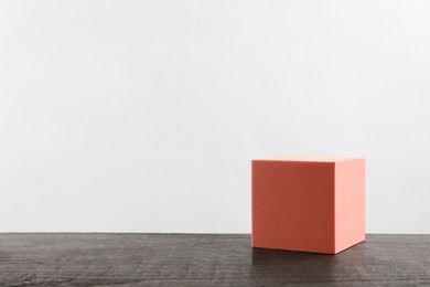 Photo of Pink cube podium on wooden table. Space for text