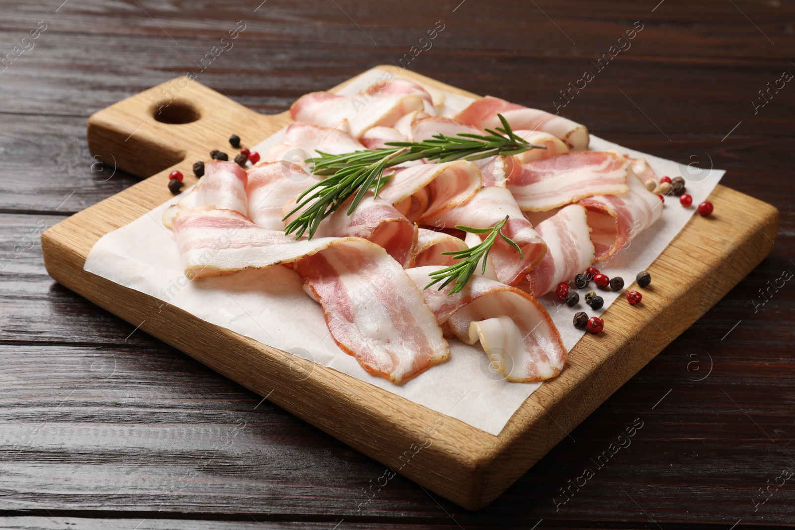 Photo of Slices of raw bacon and spices on wooden table, closeup