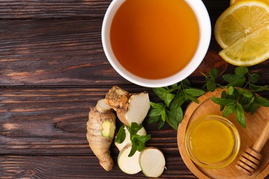Photo of Flat lay composition of tea with mint, honey, lemon and ginger on wooden table. Space for text
