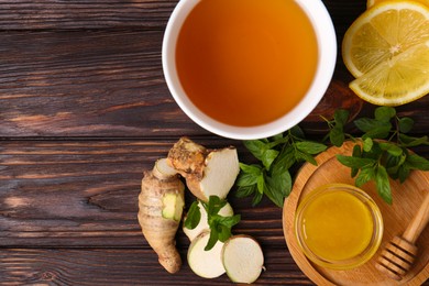 Flat lay composition of tea with mint, honey, lemon and ginger on wooden table. Space for text