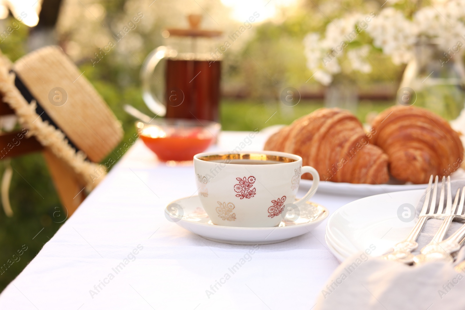 Photo of Stylish table setting with tea and croissants in spring garden