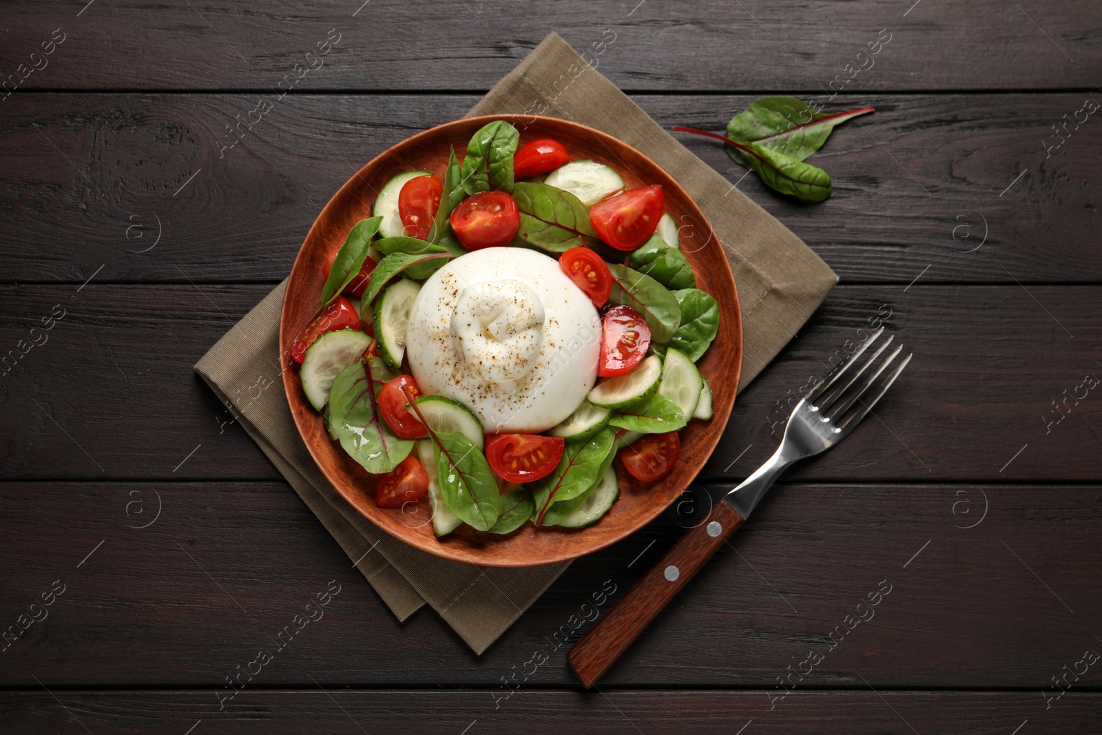 Photo of Delicious burrata salad served on wooden table, flat lay