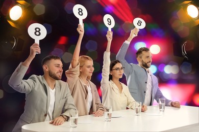 Image of Panel of judges holding different score signs at table against blurred background. Bokeh effect