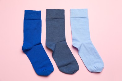Photo of Different blue socks on light pink background, flat lay