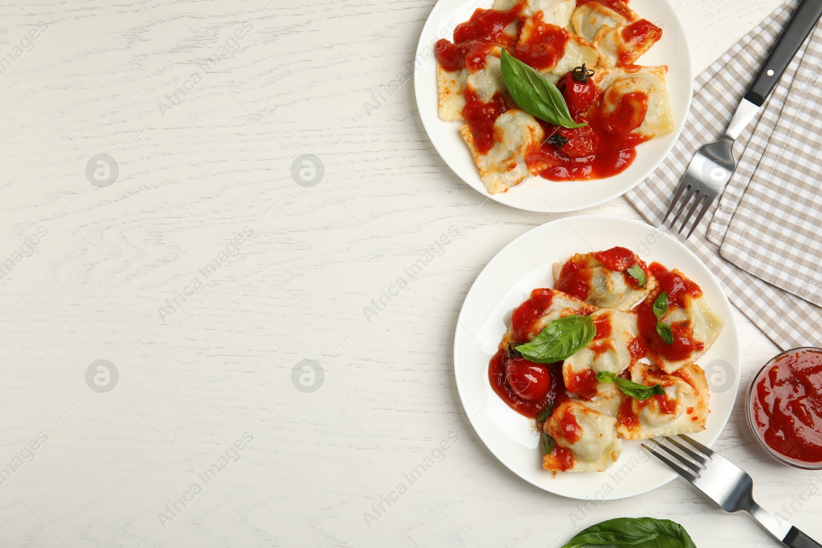 Photo of Tasty ravioli with tomato sauce served on white wooden table, flat lay. Space for text