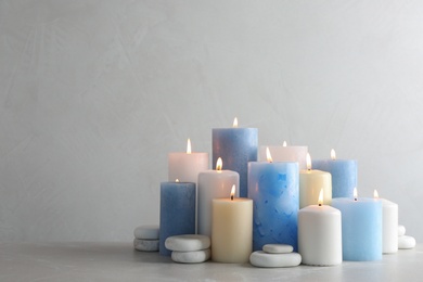 Photo of Composition with burning candles on table against light background, space for text