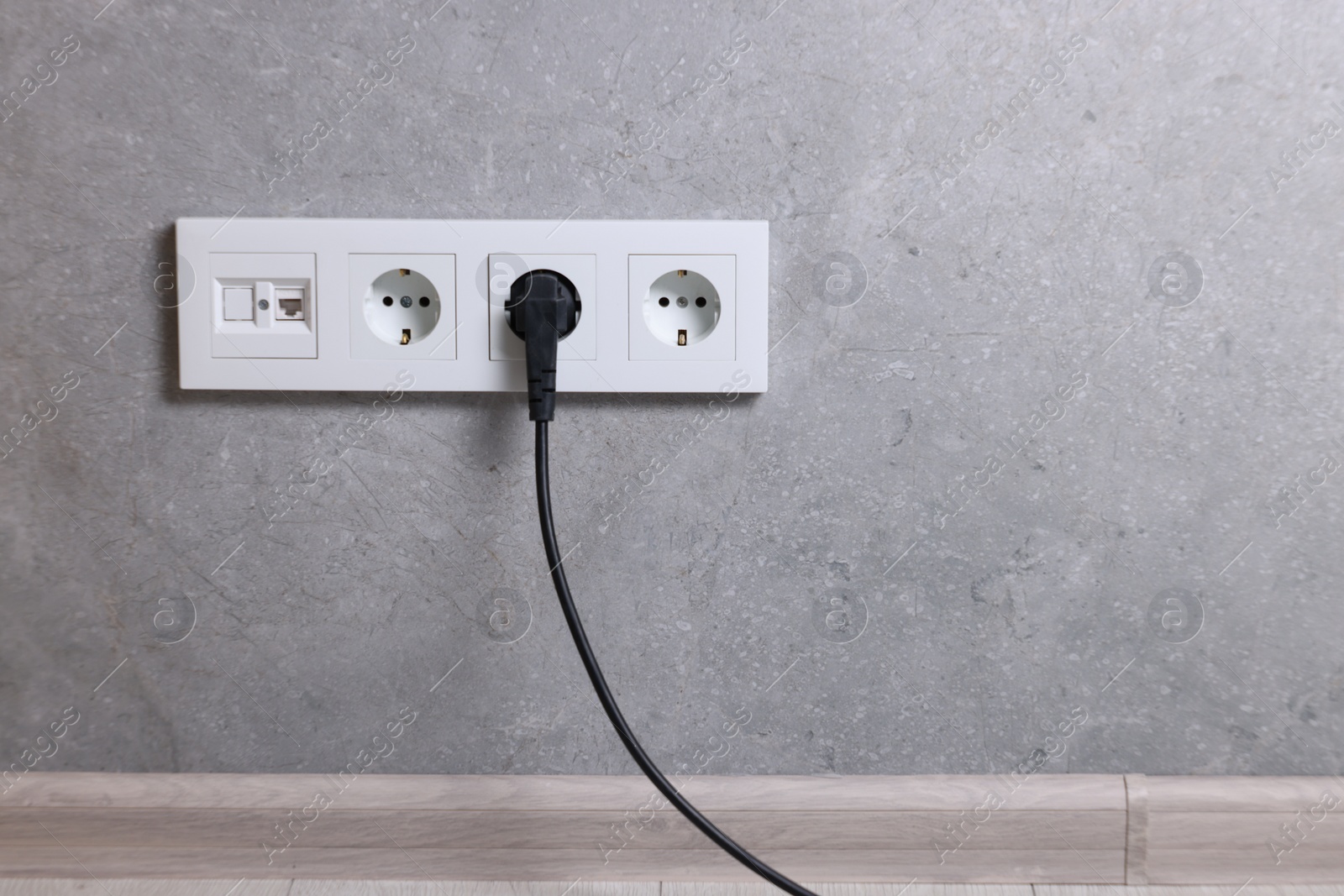 Photo of Power sockets and electric plug on grey wall, space for text