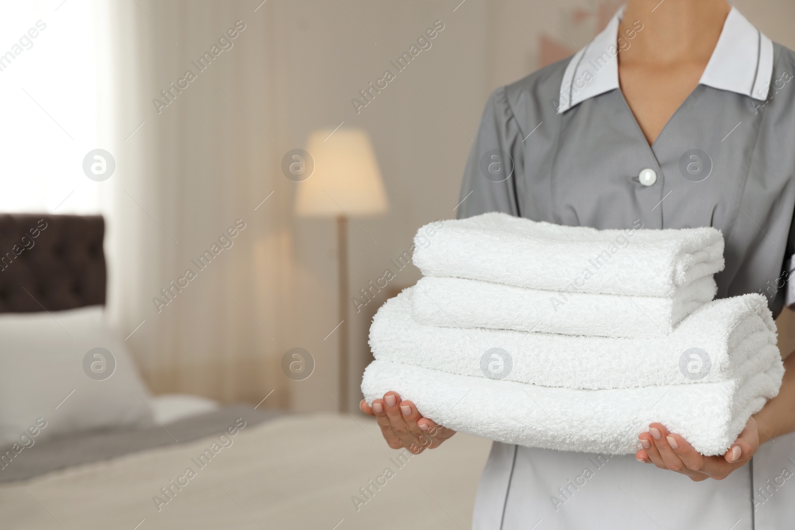 Photo of Chambermaid with stack of fresh towels in hotel room, closeup. Space for text