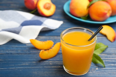 Photo of Natural peach juice and fresh fruits on blue wooden table