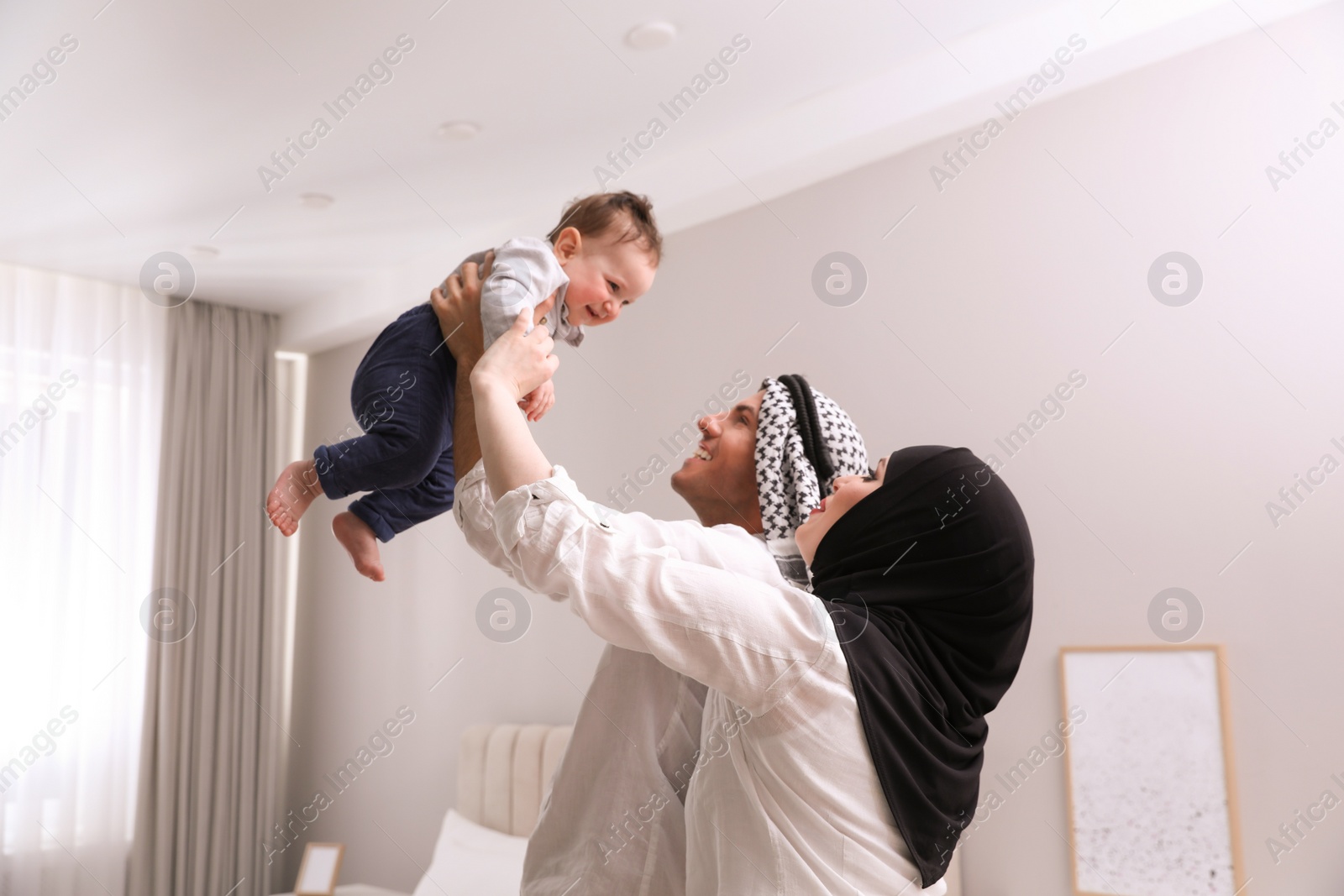 Photo of Happy Muslim family with little son in bedroom