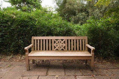 Photo of Stylish wooden bench and green plants in beautiful garden