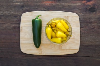 Photo of Fresh and pickled jalapeno peppers on wooden table, top view