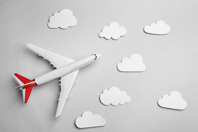 Toy airplane and clouds on light grey background, flat lay