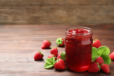 Delicious pickled strawberry jam and fresh berries on wooden table. Space for text