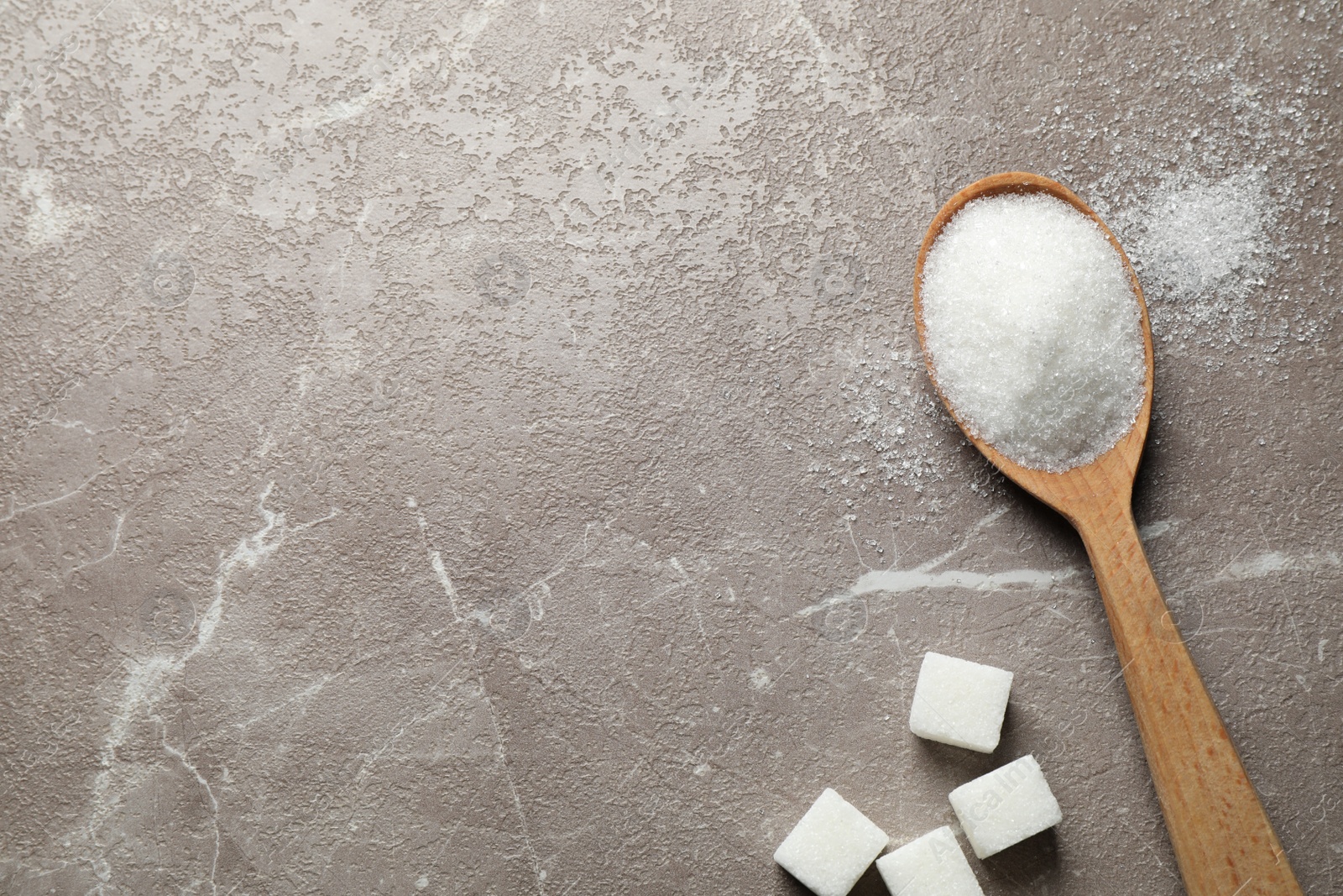 Photo of Spoon of white sugar on marble table, flat lay. Space for text