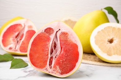 Photo of Different tasty pomelo fruits on white marble table, closeup