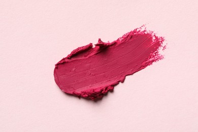 Photo of Smear of bright lipstick on light background, top view