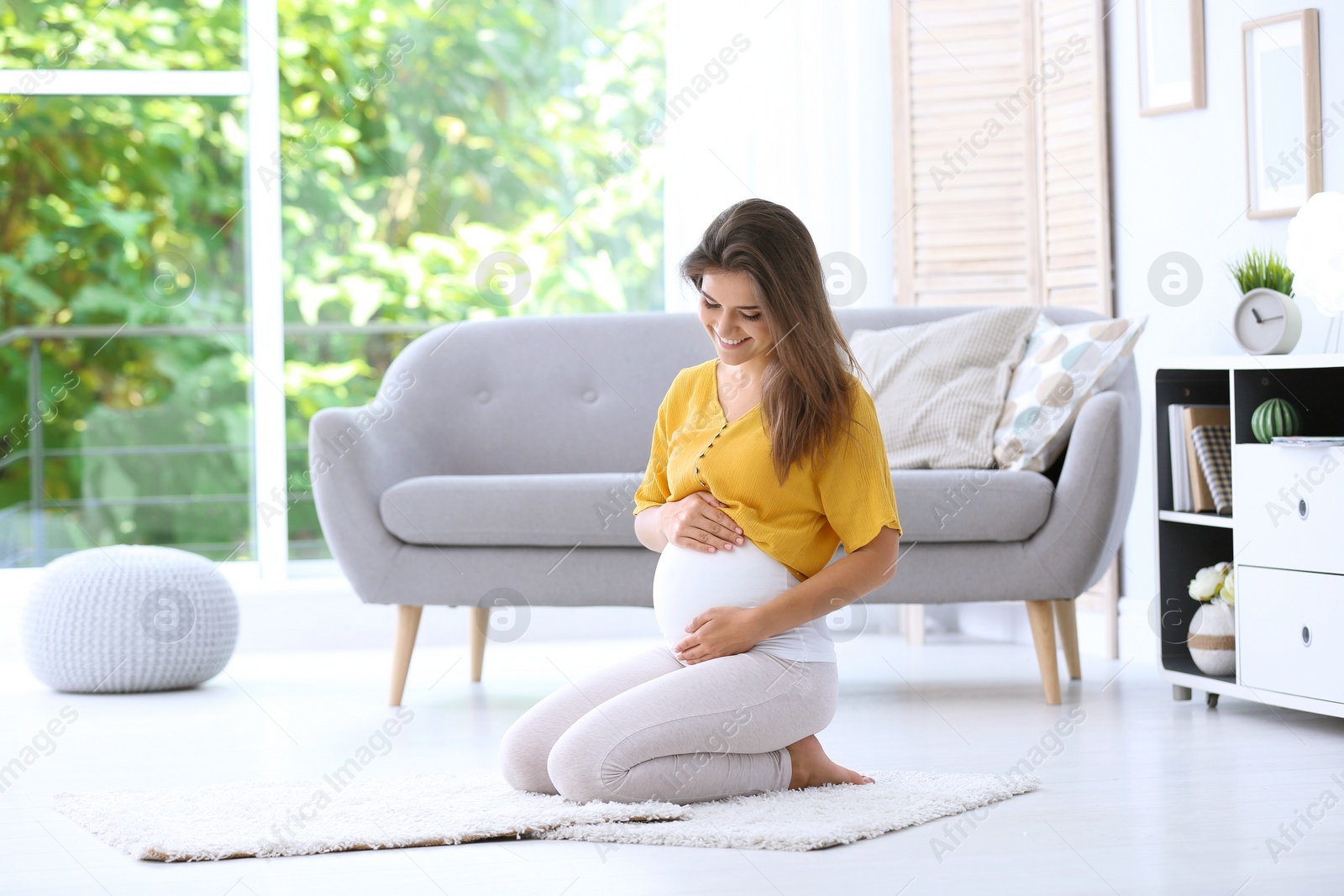 Photo of Happy pregnant woman sitting on floor at home