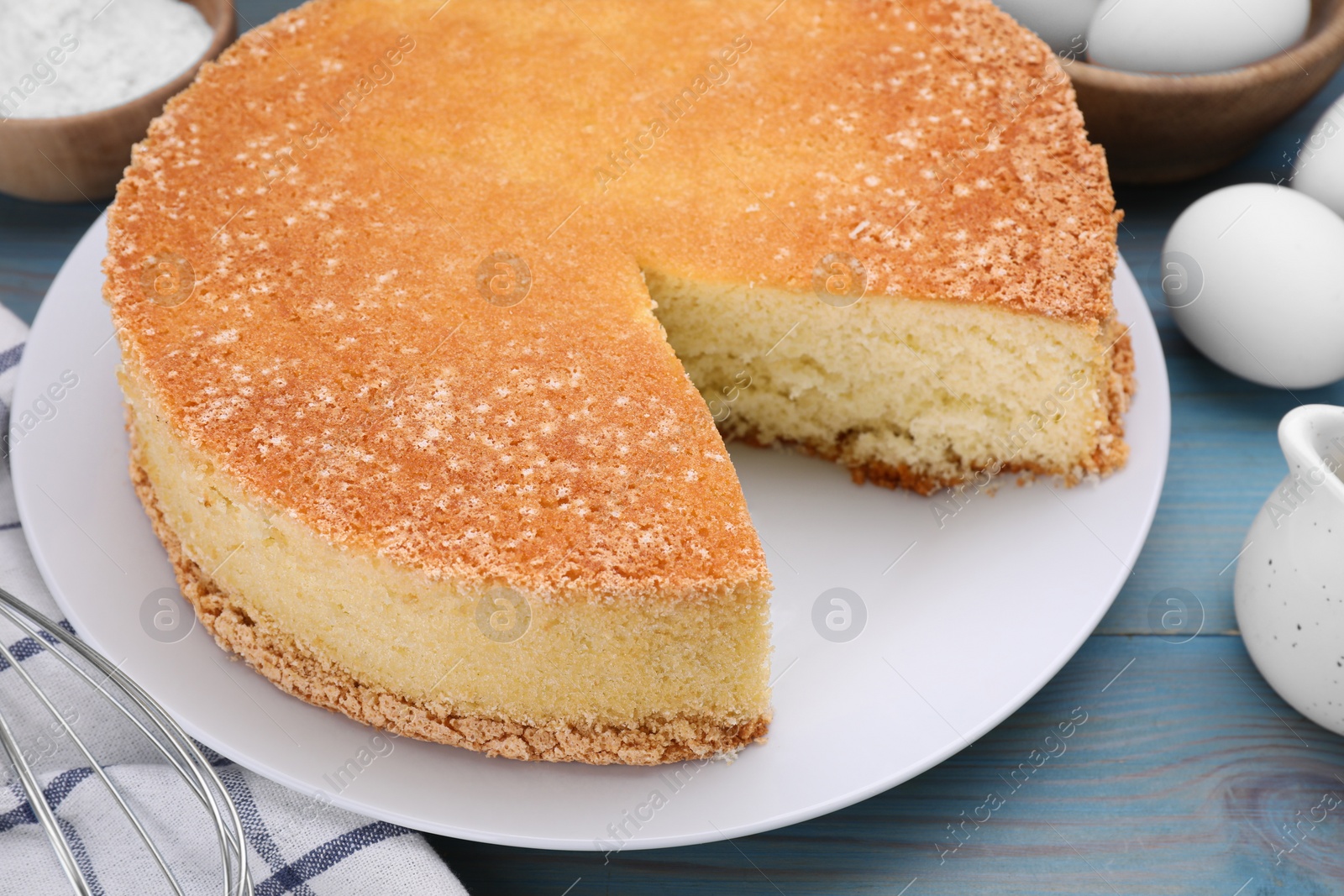 Photo of Tasty sponge cake on light blue wooden table, closeup