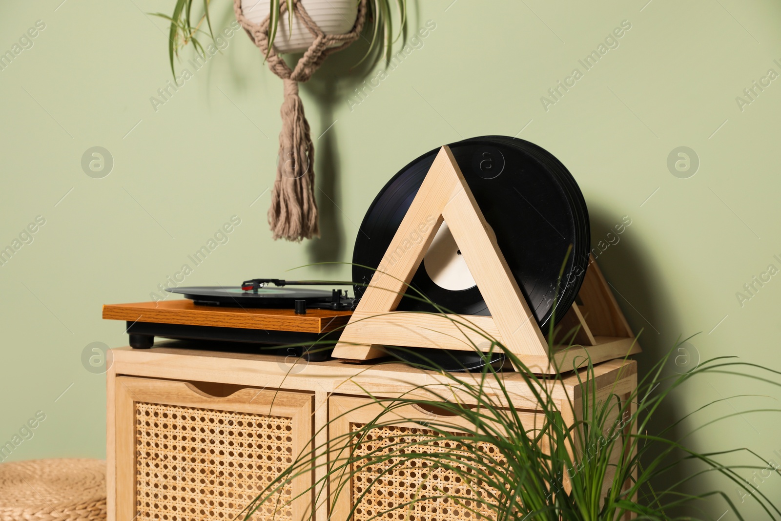 Photo of Vinyl records and player on wooden cabinet near light green wall
