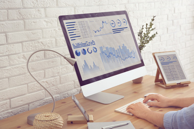 Image of Young man using modern computer at table, closeup. Fintech concept