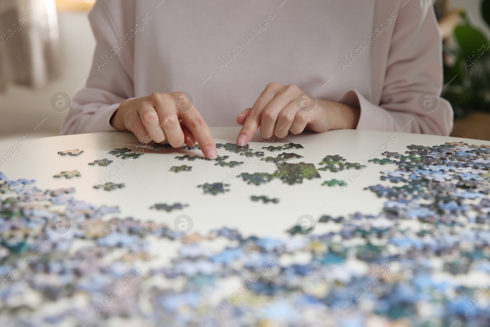 Photo of Young woman playing with puzzles at table, closeup