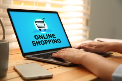 Woman using laptop for online shopping at wooden table, closeup