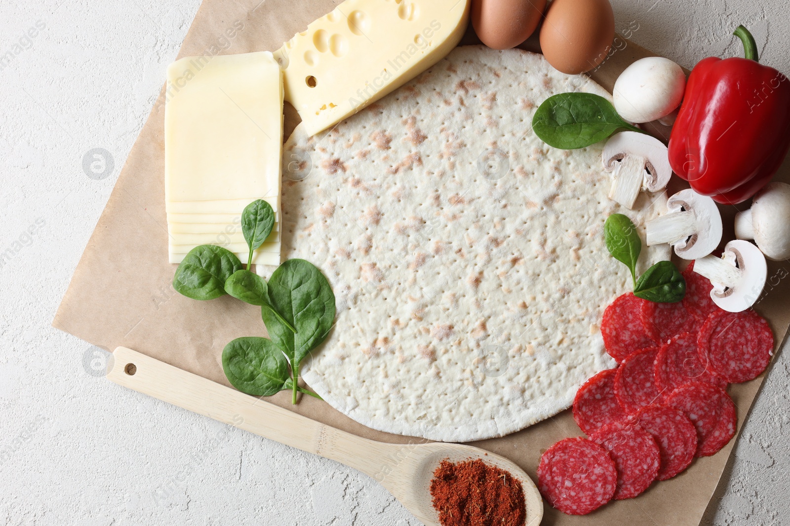 Photo of Pizza base and products on light textured table, top view