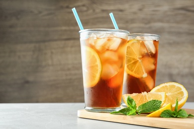 Photo of Glasses of refreshing iced tea on light table against wooden background