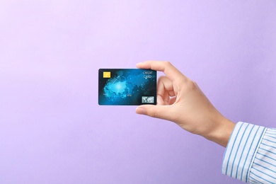 Woman holding credit card on color background